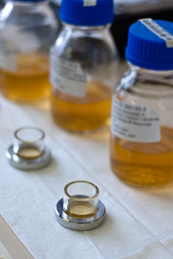 A close up image of microscope chambers in front of sample bottles of transcluscent yellow liquid.