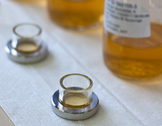 A close up image of microscope chambers in front of sample bottles of transcluscent yellow liquid.
