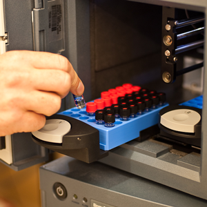 A close up image of a hand placing a vial into an instrument.